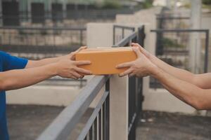 asiático entrega Rápido mensajero joven hombre utilizar dando cajas a mujer cliente él vistiendo protector cara máscara a frente hogar foto