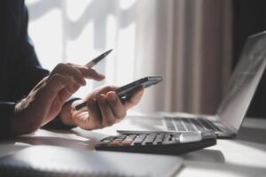 Side view shot of a man's hands using smart phone in interior, rear view of business man hands busy using cell phone at office desk, young male student typing on phone sitting at wooden table, flare photo