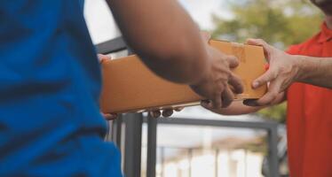 asiático entrega Rápido mensajero joven hombre utilizar dando cajas a mujer cliente él vistiendo protector cara máscara a frente hogar foto