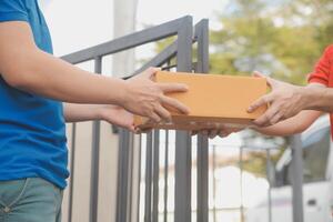 Asian delivery express courier young man use giving boxes to woman customer he wearing protective face mask at front home photo