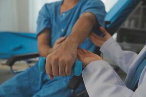 Physiotherapist man giving exercise with dumbbell treatment About Arm and Shoulder of athlete male patient Physical therapy concept photo