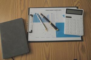 Close up view of simple workspace with laptop, notebooks, coffee cup and tree pot on white table with blurred office room background photo