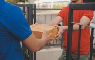 asiático entrega Rápido mensajero joven hombre utilizar dando cajas a mujer cliente él vistiendo protector cara máscara a frente hogar foto