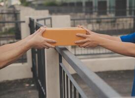 asiático entrega Rápido mensajero joven hombre utilizar dando cajas a mujer cliente él vistiendo protector cara máscara a frente hogar foto