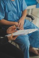 Midsection of female nurse checking blood pressure of woman sitting on wheelchair in clinic photo