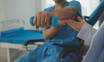 Physiotherapist man giving exercise with dumbbell treatment About Arm and Shoulder of athlete male patient Physical therapy concept photo