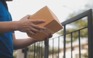 Asian delivery express courier young man use giving boxes to woman customer he wearing protective face mask at front home photo