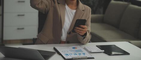Young happy business woman, smiling pretty professional businesswoman worker looking at smartphone using cellphone mobile technology working at home or in office checking cell phone sitting at desk. photo
