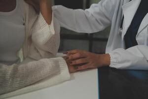 Doctor giving hope. Close up shot of young female physician leaning forward to smiling elderly lady patient holding her hand in palms. Woman caretaker in white coat supporting encouraging old person photo