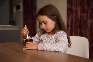 adorable pequeño niño niña comiendo delicioso chocolate vegano yogur para desayuno. sano comiendo y dieta concepto. comida y bebida consumismo. foto