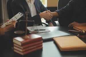 Justice and Law concept. Legal counsel presents to the client a signed contract with gavel and legal law or legal having team meeting at law firm in background photo