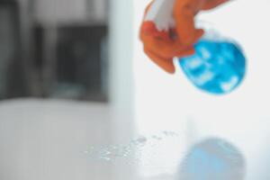 Woman cleaning table using rag and diffuser at home. photo