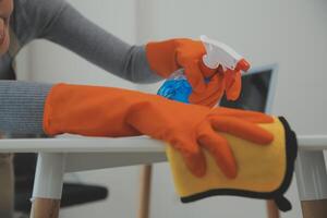 Woman cleaning table using rag and diffuser at home. photo