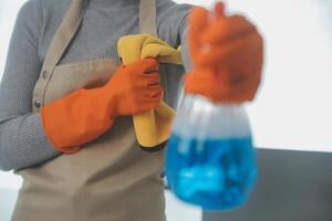 Woman cleaning table using rag and diffuser at home. photo