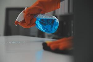 Woman cleaning table using rag and diffuser at home. photo