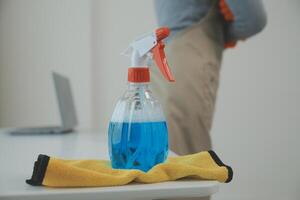 Woman cleaning table using rag and diffuser at home. photo