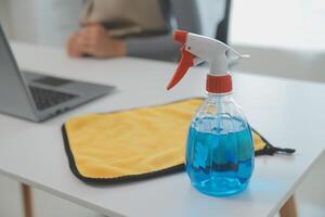 Woman cleaning table using rag and diffuser at home. photo