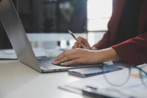 Cropped image of professional businesswoman working at her office via laptop, young female manager using portable computer device while sitting at modern loft, flare light, work process concept photo