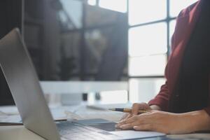 Cropped image of professional businesswoman working at her office via laptop, young female manager using portable computer device while sitting at modern loft, flare light, work process concept photo