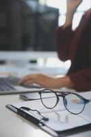 Cropped image of professional businesswoman working at her office via laptop, young female manager using portable computer device while sitting at modern loft, flare light, work process concept photo