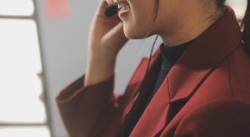 Friendly female helpline operator in call center. Young woman working in call center and holding microphone on headset with hand. photo