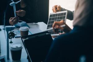 verde energía negocio empresa reunión con negocio personas planificación y discutir márketing de sostenible y renovable limpiar energía producto con solar célula y viento turbina generador. pionero foto