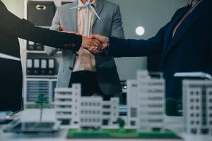 Two business executives, elegantly attired in suits, join hands in a gesture of unity, solidarity, and shared commitment towards a common goal or venture. photo