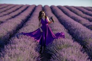 A woman in a purple dress is standing in a field of lavender. She is holding a bouquet of flowers and she is enjoying the beauty of the flowers. Concept of serenity and appreciation for nature. photo