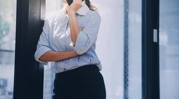 Portrait of a happy Asian businesswoman using mobile phone indoor, Asian businesswoman working in modern office. photo