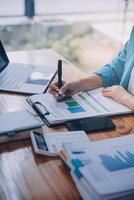 Asian Business woman using calculator and laptop for doing math finance on an office desk, tax, report, accounting, statistics, and analytical research concept photo