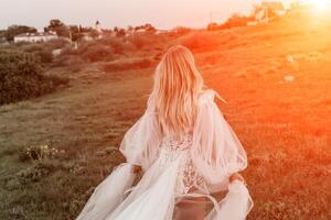 beautiful young bride in a field at sunset photo