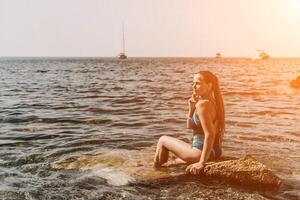 Woman travel summer sea. A happy tourist in a blue bikini enjoying the scenic view of the sea and volcanic mountains while taking pictures to capture the memories of her travel adventure. photo