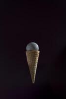A microphone is placed inside of an ice cream cone. The cone is upside down and the microphone is suspended in the air. photo