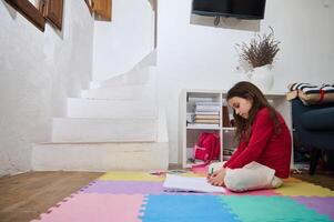 Smart elementary age schoolkid girl engaged on doing homework, solving problems, writing on an exercise book. The concept of back to school. Education, Studying, Distance learning at home photo