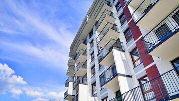 A view at a detail of a modern white apartment building with blue sky background. photo