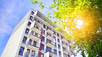 Modern residential building with new apartments in a green residential area. Eco architecture. Green tree and new apartment building. The harmony of nature and modernity. photo