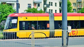 Warsaw, Poland. 28 April 2024. Modern red and yellow trams on street. Public transport. photo