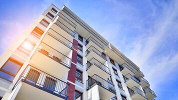 A view at a detail of a modern white apartment building with blue sky background. photo