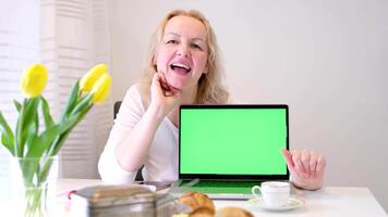 anuncio en ordenador portátil verde pantalla chromakey hermosa mujer sonriente mirando a cámara riendo con abierto boca haciendo ojos anunciar interesante producto desayuno comida Cocinando espectáculo video