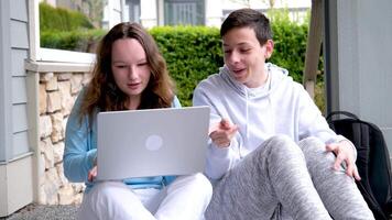 Junge umklammern Kopf Lachen Mädchen halten Laptop Aufpassen Film interessant Clips Anzeige lösen Probleme Schulkinder freunde zusammen Kindheit Liebe Jugend Jugendliche Sitzung draußen auf Schritte video