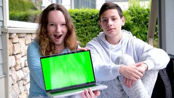 serious teenagers stand with laptop and backpack schoolbag show green screen chroma key on laptop autumn spring study stand near home advertise online learning language courses boy and girl video