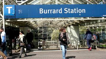 People get out of the skytrain station on the sign says Burrard Station adults young in jackets in scarves with bags with a gray-haired man with a beard different people of different nationalities video