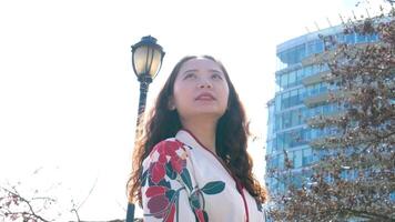 woman in Voncouver kimono dress looking sakura flower or cherry blossom blooming in the garden video