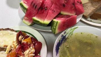 enkel mat på de tabell soppa bröd ister kotlett ris och tomat sallad muggar i de sjukhus mat vattenmelon sommar tid skedar gafflar salt video