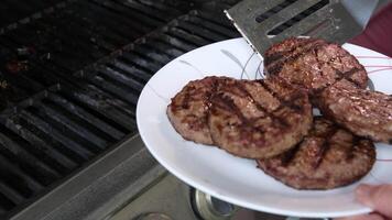 Barbecuing plant based Impossible Burger patties on electric grill semi close up shot panning over spatula flipped and grilled brown seasoned burger patties video