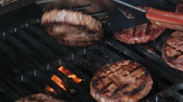 Barbecuing plant based Impossible Burger patties on electric grill semi close up shot panning over spatula flipped and grilled brown seasoned burger patties video