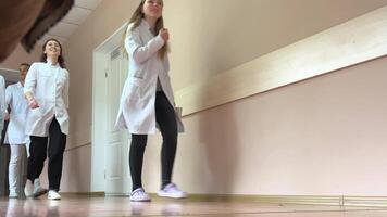 hospital young trainee doctors are walking along corridor with folders and notebooks in hands young women in white coats treat study university practice in real life Ukraine Vinnitsa video