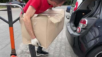 nieuw mail bagage gedeelte levering van groot pakketten dozen laden in de auto kwestie bagage levering Mens in een rood t-shirt uniform trolley levering Oekraïne vinnitsa video