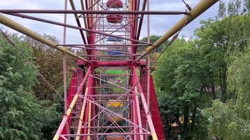 filmando uma a partir de uma ferris roda dentro a cidade do vinnitsa, Ucrânia velho atrações Visão do a cidade alta ferro roda dentro a parque colorida cestas verde árvores chuvoso céu video