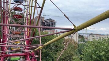 filming a from a Ferris wheel in the city of Vinnitsa, Ukraine old attractions view of the city Tall iron wheel in the park colorful baskets green trees rainy sky video